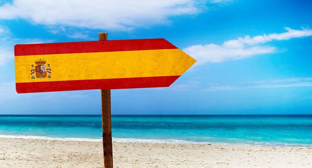 Drapeau d'Espagne sur panneau de table en bois sur fond de plage. C'est signe d'été de l'Espagne
. - Photo, image
