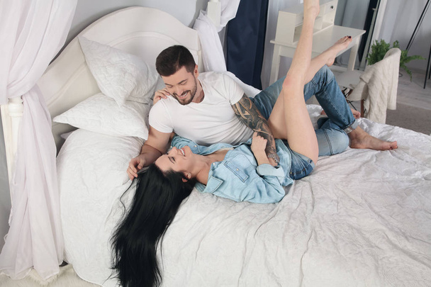 Young couple lying in bed and laughing while tickling each other - Photo, Image