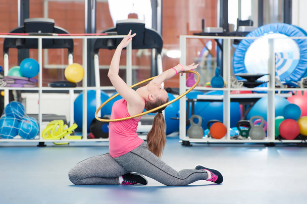 Beautiful young woman doing gimnastics on the floor with hoop. - Zdjęcie, obraz