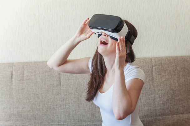 Jonge vrouw glimlach dragen met behulp van virtuele realiteit Vr bril helm headset thuis - Foto, afbeelding