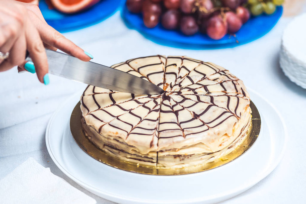 Womans hands cut whole esterhazy torte cake with knife. Authentic recipe, hungarian and austrian dessert, view from above, close-up - Foto, imagen