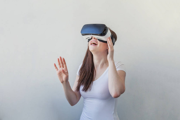 Beyaz arka plan üzerinde sanal gerçeklik Vr gözlük kask kulaklık kullanarak giyen gülümseme genç kadın - Fotoğraf, Görsel