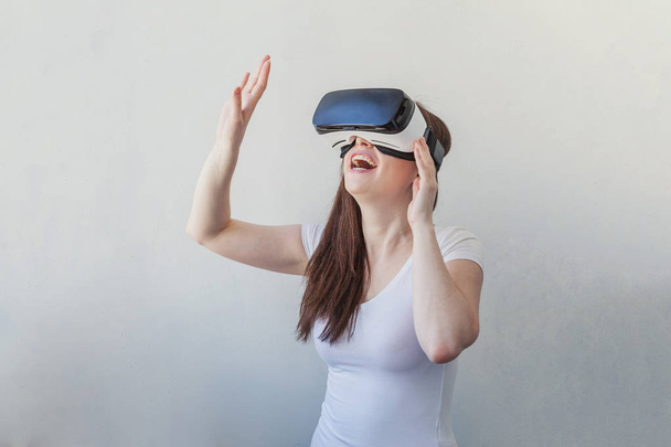 Sonríe mujer joven usando realidad virtual gafas VR casco auriculares sobre fondo blanco
 - Foto, imagen
