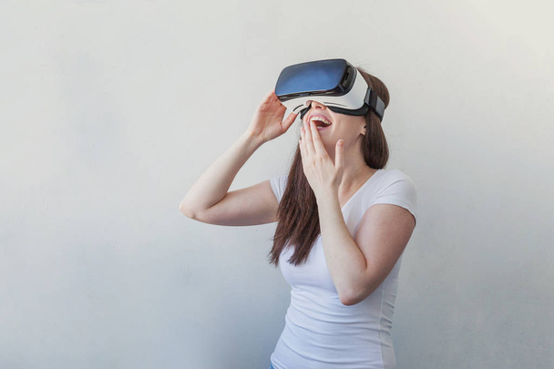 Посміхайтеся, молода жінка вдягнена за допомогою гарнітури VR окулярів на білому тлі
 - Фото, зображення