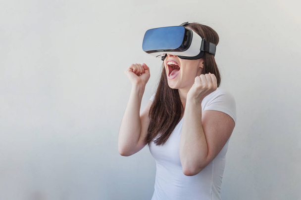 Hymyile nuori nainen yllään käyttäen virtuaalitodellisuus VR lasit kypärä kuulokkeet valkoisella taustalla
 - Valokuva, kuva