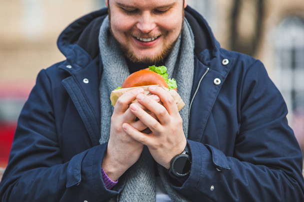 genç yetişkin adam yeme hamburger - Fotoğraf, Görsel