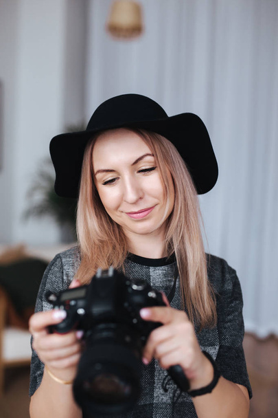 Young blonde stylish photographer is looking photo on camera. blogger hobby content concept - Valokuva, kuva