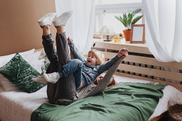 Cheerful little boy having fun with mother on sofa - Foto, Imagen