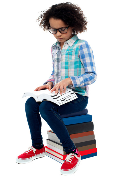 Young kid sitting on stack of books and reading - Foto, Imagen