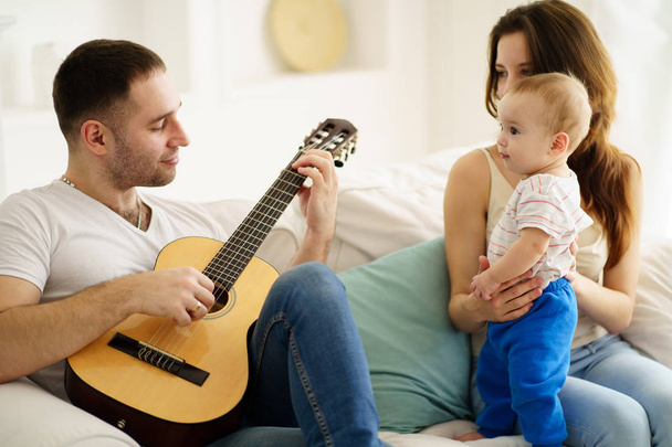 father playing guitar for mother and son. leisure - Foto, Imagen