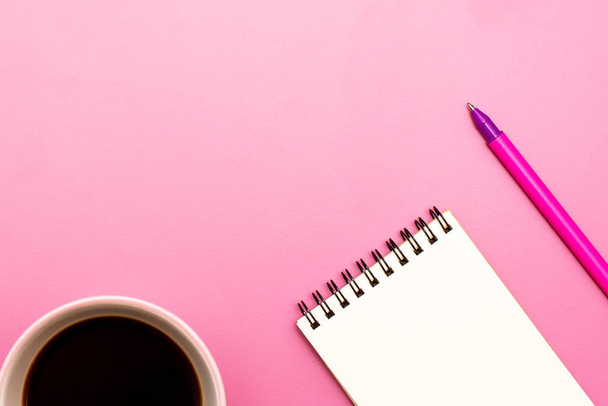 Cuaderno en blanco con espiral para la aplicación de etiquetas, café y bolígrafo sobre fondo rosa
 - Foto, Imagen