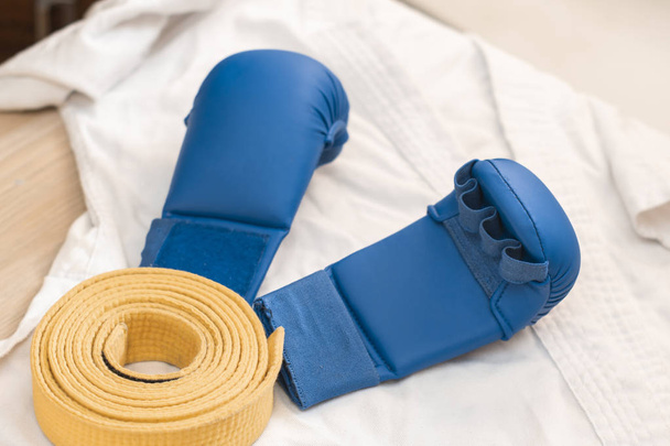 sports equipment for karate - white kimono, lining blue and yellow belt - Fotografie, Obrázek