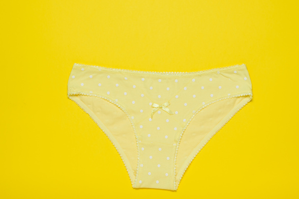 Yellow women's cotton panties on a bright yellow background. Fashionable concept. Beautiful lingerie. The view from the top. - Photo, Image