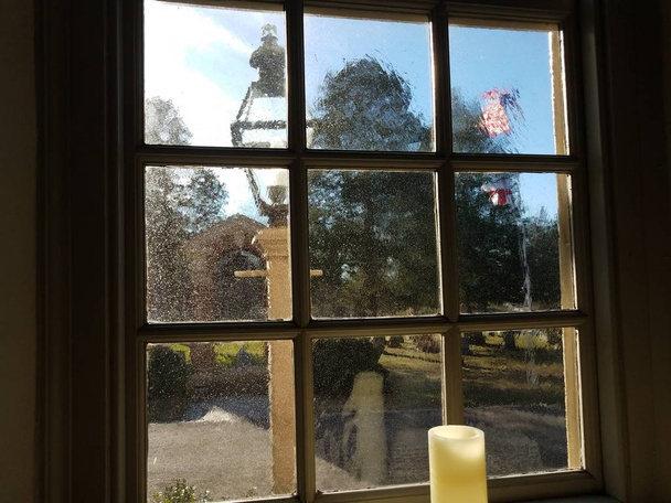 kaars, dik glas venster en vlag buiten - Foto, afbeelding