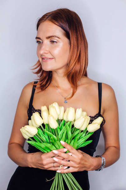 Young woman holding bouquet of yellow tulips in hands - Foto, afbeelding