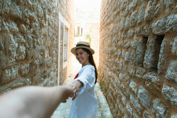 follow me concept. woman holding man hand in tight stone street of Budva - Photo, Image