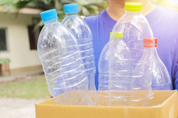 Man holds a paper box with a plastic bottle. To bottle the produ - 写真・画像
