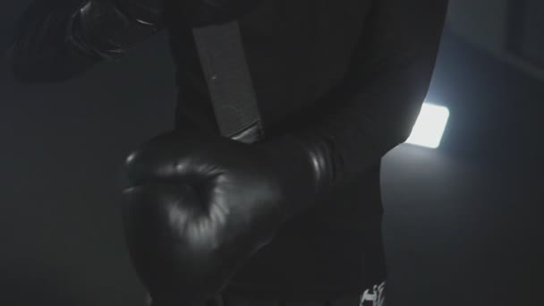 Close-up of kickboxer wearing boxing gloves against black background - Filmati, video