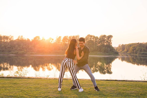 Romantique, danse sociale, concept de personnes - jeune couple dansant bachata près du lac dans une journée ensoleillée
 - Photo, image