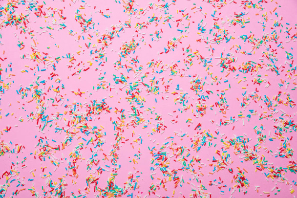 Verjaardag concept. Kleurrijke hagelslag op roze achtergrond - Foto, afbeelding