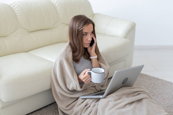 Фриланс, свобода и люди - молодая женщина с чашкой горячего напитка, сидящая на полу и работающая дома за ноутбуком
 - Фото, изображение