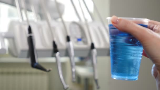 Moderne tandheelkundige kliniek. Medische apparatuur in disfocus met plastic beker met blauwe aseptische vloeistof vooraan. 4k - Video