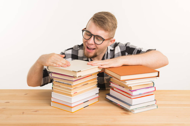 People, knowledge and education concept - smiling man sitting at the wooden table with books - 写真・画像