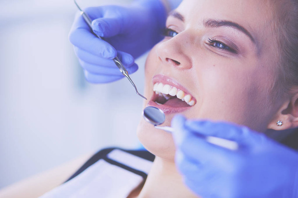 Dişçi muayenehanesinde diş muayenesi yapan ağzı açık genç bir kadın hasta.. - Fotoğraf, Görsel