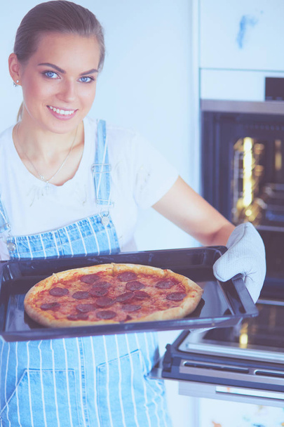 Happy young woman cooking pizza at home - Foto, Bild
