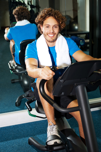 Handsome man at the gym doing static cycling - 写真・画像