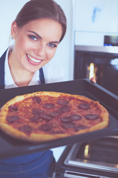 Щаслива молода жінка готує піцу вдома
 - Фото, зображення