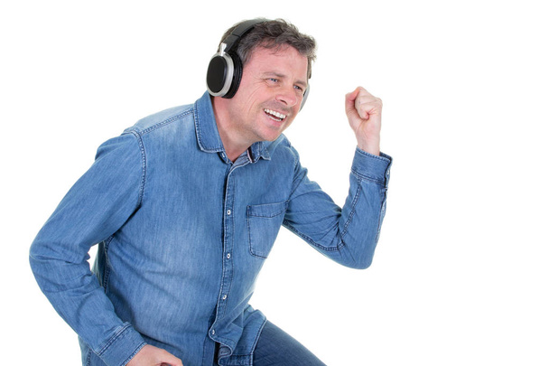 knappe man blauw shirt dragen is permanent met een vrolijke glimlach en dansen met zijn ogen gesloten over de witte achtergrond - Foto, afbeelding