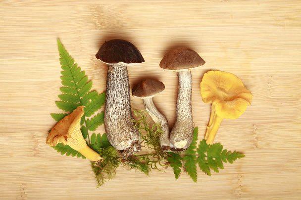 mushrooms and leaves of fern on a wooden background - Fotografie, Obrázek