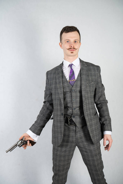 vintage English detective with a checkered business suit with a gun on a white studio solid background - Фото, изображение