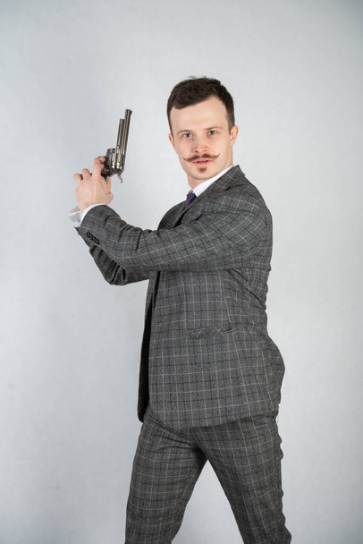 vintage English detective with a checkered business suit with a gun on a white studio solid background - Foto, immagini