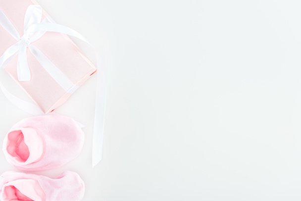 bovenaanzicht van Pink booties en geschenkdoos op witte achtergrond met kopieerruimte  - Foto, afbeelding