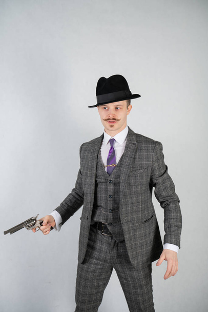 vintage English detective with a checkered business suit with a gun on a white studio solid background - Foto, afbeelding