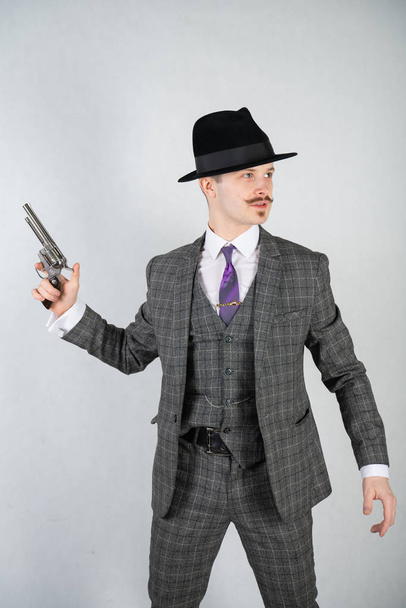 vintage English detective with a checkered business suit with a gun on a white studio solid background - Foto, Imagem