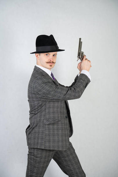 vintage English detective with a checkered business suit with a gun on a white studio solid background - Fotoğraf, Görsel