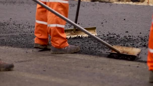 Herverdeling nieuwe rad. asfalt op de weg. Gladstrijken van de weg. Werknemers werken buiten. Bitumen - Video