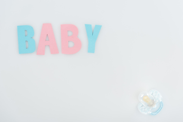 top view of pacifier and pink and blue baby lettering isolated on white with copy space - Photo, Image