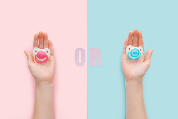 partial view of women holding pacifiers with or lettering on blue and pink background - Foto, Imagem