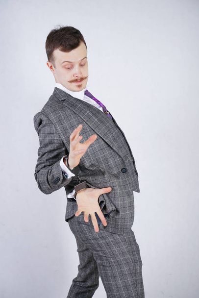 expensively dressed thief suffers from kleptomania and is arrested for a crime. a man in a business fashionable suit stands on a white background in the Studio. - Фото, зображення