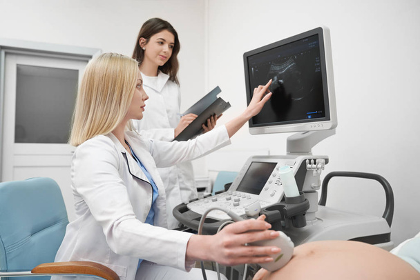 Doctors doing ultrasound diagnosis of pregnant woman. - 写真・画像