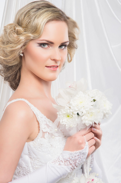 Young and beautiful bride standing with the flower bouquet - Foto, afbeelding