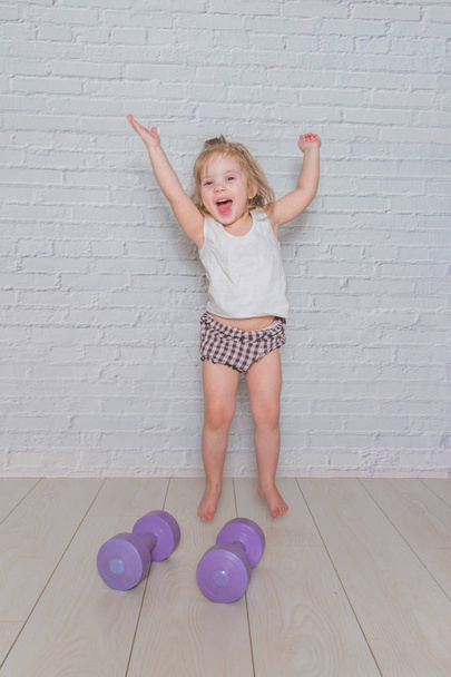 girl, the child is engaged in fitness with dumbbells, against a  - Foto, Imagem