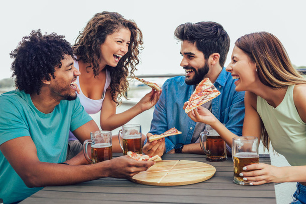 Freunde, die Pizza genießen. Gruppe junger fröhlicher Menschen beim Pi-Essen - Foto, Bild