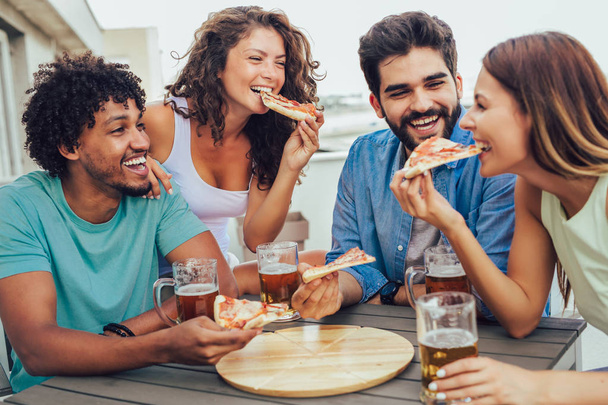 Freunde, die Pizza genießen. Gruppe junger fröhlicher Menschen beim Pi-Essen - Foto, Bild