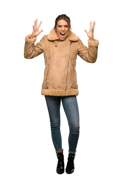 A full-length shot of a Blonde woman with a coat with surprise and shocked facial expression over isolated white background - Fotoğraf, Görsel