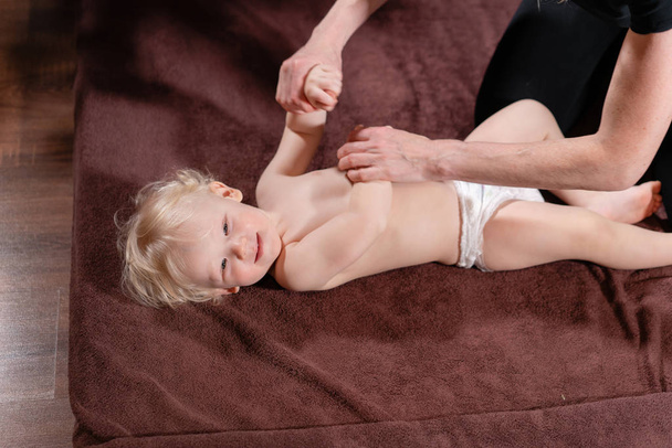 Massage bébé. Mère ou thérapeute fait un massage à son bébé à la maison. Soins de santé et concept de médecine. Blond garçon
 - Photo, image